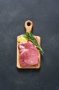 Fresh raw meat on a wooden board with rosemary and lemon on a black background, pork Royalty Free Stock Photo