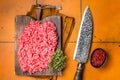 Fresh Raw Mince, Ground beef and pork meat on a butcher board. Orange background. Top view Royalty Free Stock Photo