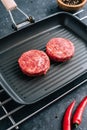 Fresh raw minced beef steak for burgers on black grill pan with chili pepper Royalty Free Stock Photo