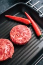 Fresh raw minced beef steak for burgers on black grill pan with chili pepper Royalty Free Stock Photo