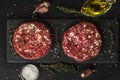 Fresh raw minced meat beef burgers patties on black slate board with spices and herbs for cooking on black background Royalty Free Stock Photo