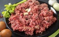 Fresh raw minced meat with garlic cloves on a black plate Royalty Free Stock Photo