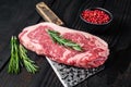 Fresh Raw new york strip beef steak on a butcher meat cleaver. Black wooden background. Top view