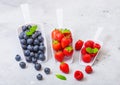 Fresh raw organic berries in white scoop spoon on kitchen table background.Top view. Strawberry, Raspberry, Blueberry and Mint lea Royalty Free Stock Photo