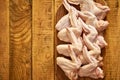 Fresh raw organic chicken wings on chopping board on wooden table.