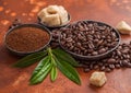 Fresh raw organic coffee beans with ground powder and cane sugar cubes with coffee trea leaf on light brown background