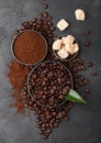 Fresh raw organic coffee beans with ground powder and cane sugar cubes with coffee trea leaf on black background
