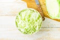 Fresh raw organic shredded white cabbage in ceramic bowl halved head on wood cutting board on kitchen table. coleslaw salad Royalty Free Stock Photo