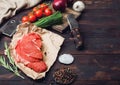 Fresh raw organic slice of braising steak fillet on butchers paper with fork and knife on dark wooden background. Red onion, Royalty Free Stock Photo