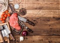 Fresh raw organic slice of braising steak fillet on chopping board with fork and knife on wooden background. Red onion, tomatoes Royalty Free Stock Photo