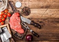 Fresh raw organic slice of braising steak fillet on chopping board with fork and knife on wooden background. Red onion, tomatoes Royalty Free Stock Photo