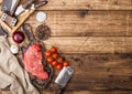 Fresh raw organic slice of braising steak fillet on chopping board with meat hatchet on wooden background. Red onion, tomatoes Royalty Free Stock Photo