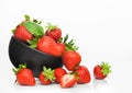 Fresh raw organic strawberries in black ceramic bowl plate on white background with berries next to it Royalty Free Stock Photo