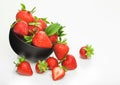 Fresh raw organic strawberries in black ceramic bowl plate on white background with berries next to it Royalty Free Stock Photo