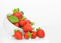 Fresh raw organic strawberries in white ceramic bowl plate on white background with berries next to it Royalty Free Stock Photo