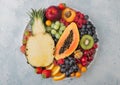 Fresh raw organic summer berries and exotic fruits in white plate on light background. Pineapple, papaya, grapes, nectarine, Royalty Free Stock Photo