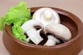 Fresh raw organic white champignon mushrooms in round wooden bowl on table background. Royalty Free Stock Photo