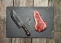 Fresh raw piece of beef meat, striploin steak on a wooden background, top view. Marbled piece of meat