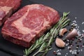 A fresh raw piece of black angus marbled meat with spices close-up on a stone dark background. Ribeye steak Royalty Free Stock Photo