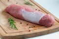 Fresh raw pork fillet with spices on wooden chopping board