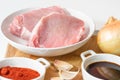 Fresh raw pork meat slices, garlic, onion, soy sauce, and some ingredients on a kitchen table Royalty Free Stock Photo