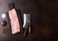 Fresh raw pork ribs on chopping board and vintage hatchets on wooden background. Pepper with salt and barbeque sauce. Space for