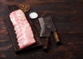 Fresh raw pork ribs on chopping board and vintage hatchets on wooden background. Pepper and salt. Space for text