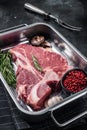 Fresh Raw porterhouse T bone beef meat Steak in steel tray with herbs. Black background. Top view Royalty Free Stock Photo