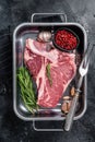 Fresh Raw porterhouse T bone beef meat Steak in steel tray with herbs. Black background. Top view Royalty Free Stock Photo