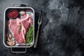 Fresh Raw porterhouse T bone beef meat Steak in steel tray with herbs. Black background. Top view. Copy space Royalty Free Stock Photo