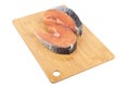 Fresh raw portioned salmon steaks on a cutting board over white background.