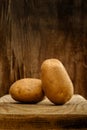 Fresh raw potatoes close-up on a board on an old wooden background. side view. artistic rustic food concept in brown tones with