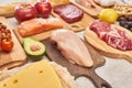 Fresh raw poultry, meat, fish on wooden cutting boards near apples, lemon, cheese, cherry tomatoes and half of avocadoes Royalty Free Stock Photo