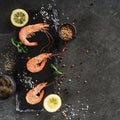 Fresh raw prawns or boiled red shrimps with spices and lemon on slate stone on dark stone background. Seafood, top view, flat lay Royalty Free Stock Photo