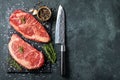 Fresh raw Prime Black Angus beef steaks on stone board: Striploin, Rib Eye. Top view with copy space. On a dark background Royalty Free Stock Photo