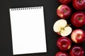 Fresh raw red apples and blank notebook on black background, top view. Flat lay, overhead, from above. Space for text Royalty Free Stock Photo