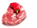 Fresh raw rib eye steak with one red chilly pepper. White isolated background, Royalty Free Stock Photo