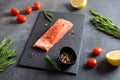 Fresh raw salmon fellet with pepper, salt, rosemary and lemon served on black stone board. Restaurant menu, healthy nutrition, Royalty Free Stock Photo