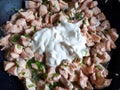 Fresh and raw salmon fillet cut in small pieces cooking on hot pan with olive oil, green onions and sour cream Royalty Free Stock Photo