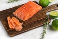 Fresh raw salmon fish fillet with rosemary and lime on wooden cutting board on white marble background. Healthy food Royalty Free Stock Photo