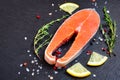 Fresh raw salmon fish steak with cooking ingredients, herbs and lemon on black background, top view Royalty Free Stock Photo