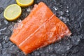 Fresh raw salmon fish steak on ice with lemon and dark stone background Royalty Free Stock Photo