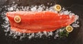 Fresh raw salmon fish steak with spices on ice over dark stone background. Creative layout made of fish, top view, flat lay Royalty Free Stock Photo