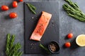 Fresh raw salmon red fish fillet with spieces, herbs, lemon and tomatoes ready for cooking on black background, top view. Royalty Free Stock Photo