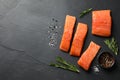 Fresh raw salmon and spices on black table, flat lay. Space for text Royalty Free Stock Photo