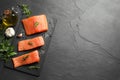 Fresh raw salmon and spices on black table, flat lay. Space for text Royalty Free Stock Photo