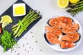 Fresh raw salmon steaks with vegetables and spices: asparagus, tomatoes, peppercorns, rucola, lemon and olive oil on gray backgrou Royalty Free Stock Photo