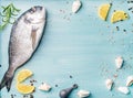 Fresh raw sea bream fish decorated with lemon slices, spices and shells on blue wooden background, copy space Royalty Free Stock Photo