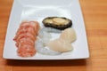 Fresh raw seafood cooking ingredients on a white plate. Peeled lobster, shrimp, prawns and abalone ready to cook Royalty Free Stock Photo