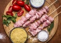 Fresh raw sliced turkey breast on skewer with bulgur, with tomato sauce and herbs with salt on a cutting board on a wooden backgr